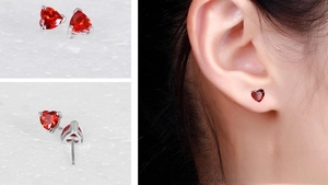 Macro detail of heart-shaped red gemstone studs with three-prong silver setting
