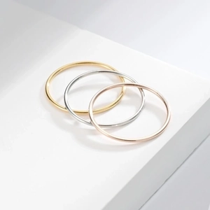 Minimalist 1mm titanium steel rings in gold, silver and rose gold on a white podium