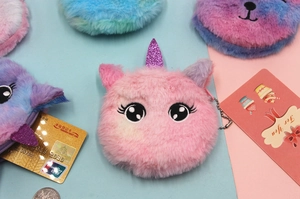 Close-up of plush unicorn coin purse with rainbow gradient fur and glittery horn detail