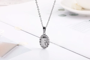 Macro shot of silver oval Virgin Mary pendant in polished stainless steel for necklaces