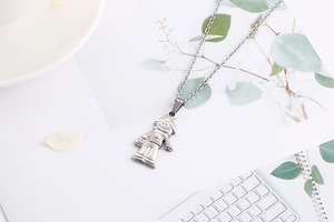 Detailed view of silver titanium steel stylized cartoon figure pendant on a white background