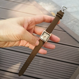 Square rose gold watch with brown strap and numeric dial shown held in hand