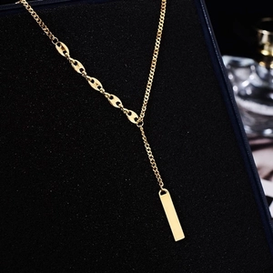 Golden Y-shaped lucky bar necklace with cuban and coffee bean link chains on black base