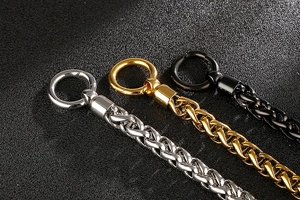 Détail de gourmettes en acier titane en argent or et noir avec des fermoirs mousquetons