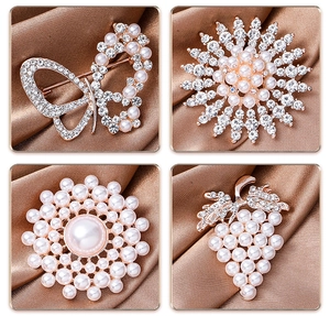 Close-up of four pearl flower brooches with rhinestones on brown silk background