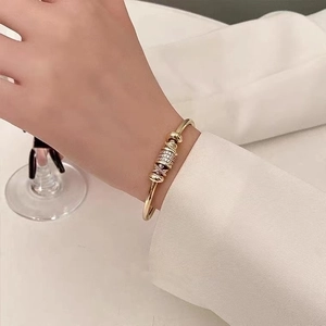 Luxurious gold open bangle with layered zircon circles on a woman wearing white suit