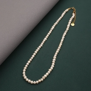 Macro detail of natural freshwater pearl necklace with gold lobster clasp and extension chain