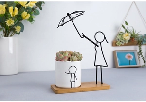 Detail of Nordic white ceramic planter with black iron umbrella figure and wooden base