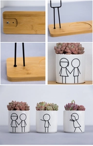 Detail of white ceramic succulent pots with human drawings and bamboo tray stand