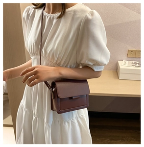 Detailed view of a dark brown crossbody square bag on a white bubble sleeve dress