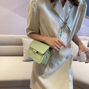 Mint green mini crossbody bag with leather texture and acrylic chain on beige dress