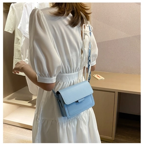 Sky blue faux leather square bag with plastic chain detail worn on a white dress