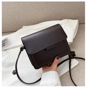 Close-up of retro dark brown matte PU leather crossbody bag with flap and knot strap