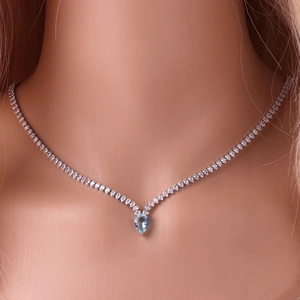 Close-up of V-shaped silver necklace with sea blue teardrop zircon on female model