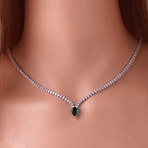 Close-up of a silver tennis necklace featuring a teardrop-shaped green gemstone pendant