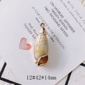 Detail of vintage conch shell pendant with gold-plated edges on a patterned background