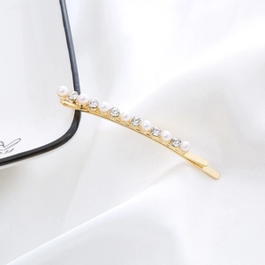 Detailed shot of golden hair clip inlaid with white pearls and sparkling rhinestones