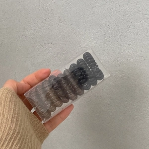 Macro detail of transparent black spiral hair ties packed in a clear branded box