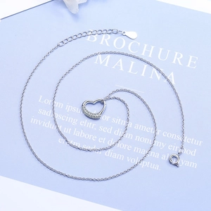 Sparkling silver heart pendant necklace with rhinestones on a minimalist blue background