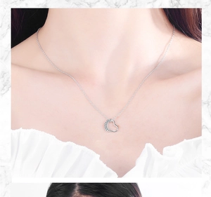 Detail view of heart pendant necklace with shimmering crystals on elegant woman's collarbone