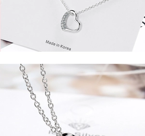 Macro detail of silver heart necklace pendant with sparkling zircon inlays on fine chain