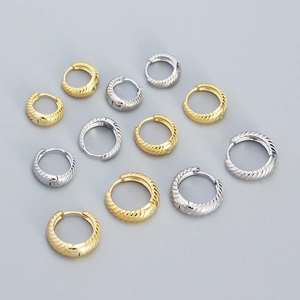 Macro shot of 925 sterling silver hoop earrings with spiral texture in gold and silver