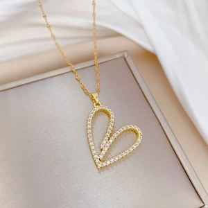 Luxurious gold heart pendant necklace with shimmering crystals on a silk background
