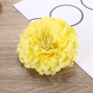 Detailed top view of a realistic yellow fabric peony flower on a wooden background