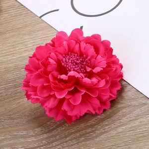 Macro shot of rose red fabric carnation flower head with detailed petals and wood background