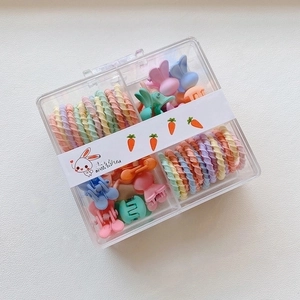 Detail of candy-colored spiral hair ties and mini claw clips in a square storage box