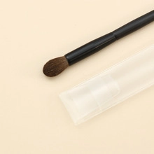 Close-up of makeup eyeshadow brush with brown bristles and clear plastic protective cover