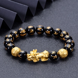 Obsidian beaded bracelet with golden PiXiu and mantra beads on dark textured surface