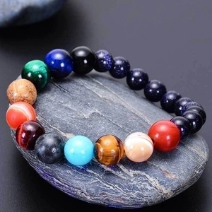 Solar system planet bracelet with natural blue sand and tiger eye stones on grey rock