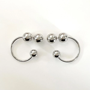 Detailed top view of silver C-shaped metallic hoop earrings with polished bead accents