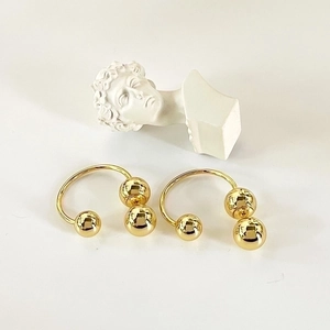 Minimalist gold arched drop earrings with polished metallic spheres on white background