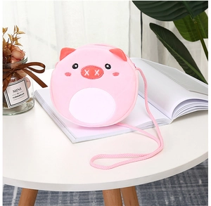 Close-up of pink plush pig crossbody bag with embroidery details on a white table