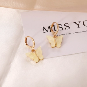 Elegant cream yellow butterfly drop earrings with golden hoops on a white silk background