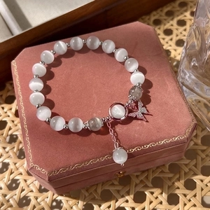 Elegant cat eye crystal bracelet with a silver butterfly charm on a pink velvet jewelry box