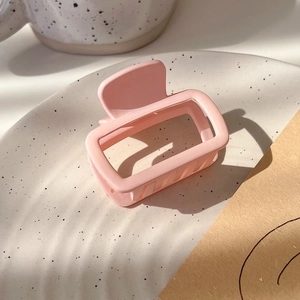 Detailed view of a matte pink square hair claw clip on a stylish ceramic plate