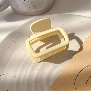 Close-up of a matte cream square hair claw clip on a ceramic tray for high ponytail styles