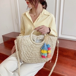 Detail of straw woven bag featuring colorful bohemian tassels and drawstring inner lining