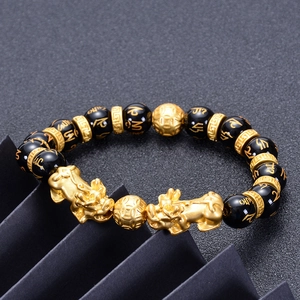 Detailed view of black onyx beads with golden mantra symbols and Pi Xiu charms