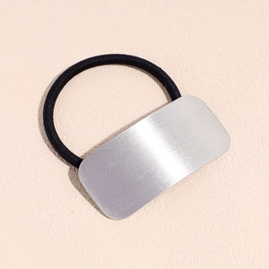 Close-up of black elastic hair tie with a rectangular silver brushed metal ornament