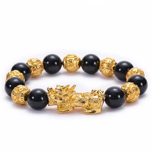 Detailed close-up of black onyx beads and golden Pi Xiu charm on a stretch bracelet