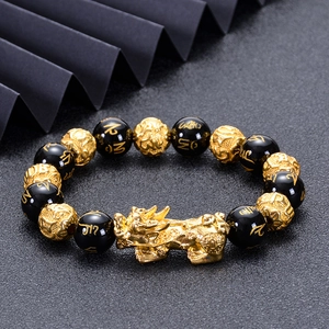 Golden Pi Xiu bracelet with black onyx beads and engraved mantras on dark background