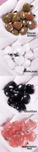 Detailed view of heart-shaped agate stone pendants held in hand with silver metal clips