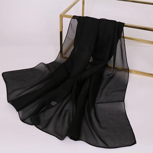 Detail showing sheer black chiffon scarf draped on a gold display stand with elegant texture
