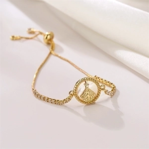 Macro shot of 3mm gold-plated religious charm bracelet with zircons and shell inlay