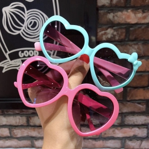 Close-up of heart-shaped sunglasses in light blue and pink with cute bow details