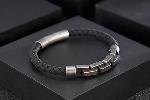 Detail of black braided leather men's bracelet with antique silver metal link accent